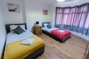 1 dormitorio con 2 camas y ventana en Beautiful 4 bedroom house with free parking Luton en Luton