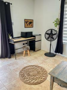 een kamer met een bureau, een ventilator en een tafel bij Lama y Solo Unique private room walking distance to the Beach in Palm-Eagle Beach