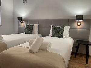 two beds in a hotel room with white sheets at Kuanza Nature Experience, Fajã do Belo in Fajã da Caldeira de Santo Cristo
