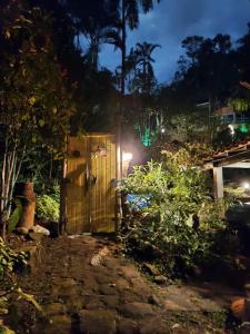 a wooden gate in a garden at night at Monte Carmelo Inn Sana in Macaé