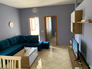a living room with a blue couch and a tv at Guest House Tian in Durrës
