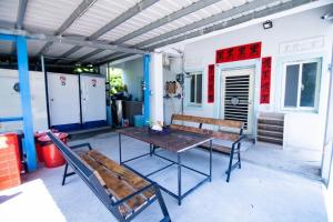 a patio with a table and benches on a building at 黑背包 Black Backpack 艙房式背包床 in Xiaoliuqiu