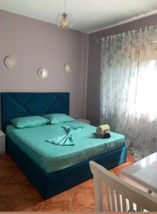 a bedroom with a bed with a blue headboard and a table at Guest House Tian in Durrës