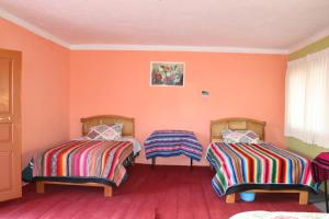 2 camas en una habitación con paredes de color naranja en LOVELAND AMANTANI LODGE - Un lugar encantado en Ocosuyo