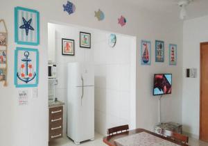 a kitchen with a refrigerator and some pictures on the wall at Praia Grande cond clube feirinha churras na sacada in Praia Grande