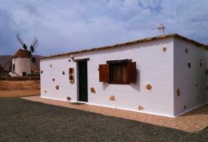 a small white building with a windmill in the background at Casa antigua en el centro de Fuerteventura in Antigua