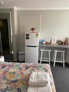 a room with a bed and a refrigerator and a table at Mandurah Apartments Sunsets in Mandurah