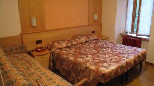 um quarto de hotel com duas camas e uma cadeira em Hotel Europa em Peio Fonti