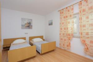 two twin beds in a room with a window at Apartments with a parking space Nemira, Omis - 4652 in Tice