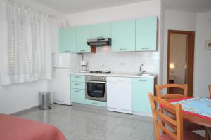 une cuisine avec des placards bleus, une table et une table dans l'établissement Apartment Medveja 3430b, à Medveja