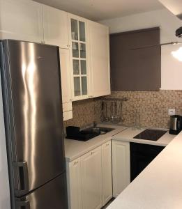 a kitchen with white cabinets and a stainless steel refrigerator at Apartments by the sea Businci, Ciovo - 4668 in Trogir