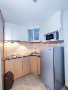 a small kitchen with a refrigerator and a microwave at TWO PALMTREE VILLAS NEWPORT BOULEVARD NEAR NAIA 3 PASAY CITY in Manila