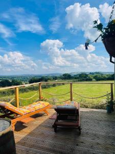 a deck with a bench and a table and a view at Red darren luxury hut in Llanveynoe
