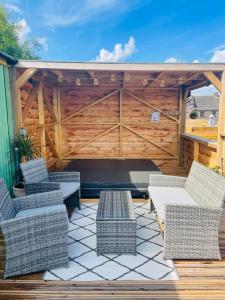 a patio with wicker chairs and a wooden fence at Red darren luxury hut in Llanveynoe