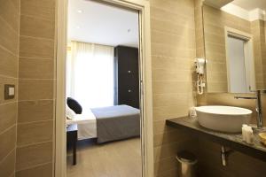 baño con lavabo, cama y espejo en Hotel Aurora en Rímini