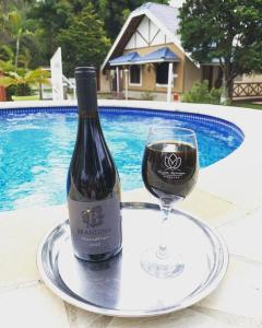 uma garrafa de vinho e um copo numa bandeja em Pousada Villa Da Montanha em São Bento do Sapucaí
