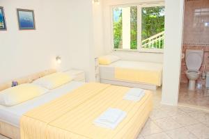 Biała sypialnia z 2 łóżkami i łazienką w obiekcie Apartments and rooms by the sea Zivogosce - Porat, Makarska - 2733 w mieście Živogošće