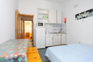 a kitchen with white cabinets and a bed in a room at Apartment Duce 2737b in Duće