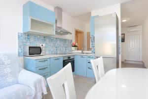 una cucina con armadi blu, tavolo e sedie di Apartments by the sea Duce, Omis - 2737 a Duće