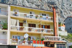 a yellow building with white balconies and flowers on it at Studio Omis 2757a in Omiš