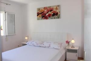 a white bed with two pillows and a painting on the wall at Apartments by the sea Mimice, Omis - 2774 in Mimice