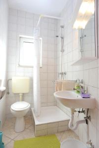 een witte badkamer met een wastafel en een toilet bij Apartments with a parking space Stanici, Omis - 2818 in Tice