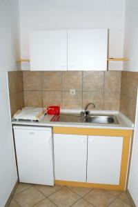 uma cozinha com armários brancos e um lavatório em Apartments with a parking space Omis - 2751 em Omiš