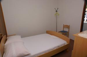 a small bedroom with a bed and a chair at Apartment Drvenik Donja vala 2732a in Drvenik