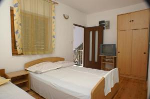 um pequeno quarto com uma cama e uma televisão em Studio Drvenik Donja vala 2732c em Drvenik
