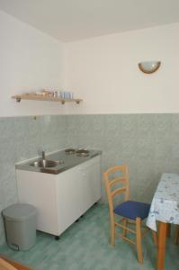 uma cozinha com um lavatório, uma mesa e uma cadeira em Studio Drvenik Donja vala 2732c em Drvenik