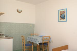 uma mesa e cadeiras numa cozinha com uma mesa e um lavatório em Studio Drvenik Donja vala 2732c em Drvenik