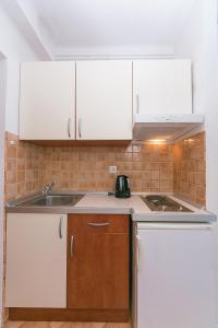 uma cozinha com armários brancos e um lavatório em Studio Brela 2752d em Brela