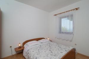 a white bedroom with a bed and a window at Apartment Postira 3065a in Postira