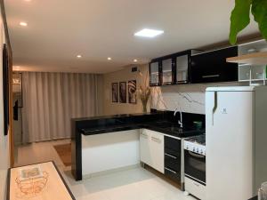 a kitchen with black and white cabinets and a refrigerator at Doce lar BV in Boa Vista