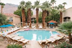 una piscina en un hotel con sillas y palmeras en L3 Oasis Hotel en Palm Springs