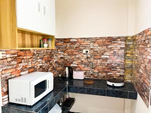 a kitchen with a microwave and a brick wall at H&Q 1BR Cozy House, Bangtao Beach in Ban Thalat Choeng Thale