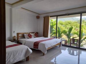 a bedroom with two beds and a large window at Mai Chau Sunset Boutique Hotel in Mai Chau
