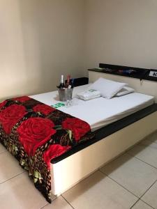 a bed in a room with red roses on it at Motel& Hotel Apê Goiânia !!! in Goiânia