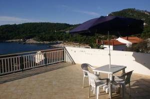 uma mesa e cadeiras numa varanda com um guarda-sol em Apartments and rooms by the sea Milna, Hvar - 3074 em Hvar