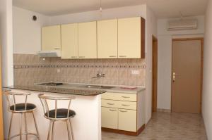a kitchen with white cabinets and two bar stools at Apartments by the sea Milna, Hvar - 3074 in Hvar
