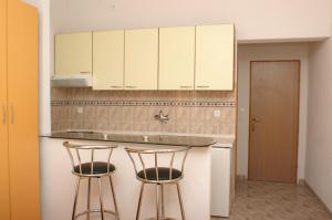 una cocina con 2 taburetes y armarios blancos en Apartments and rooms by the sea Milna, Hvar - 3074, en Hvar