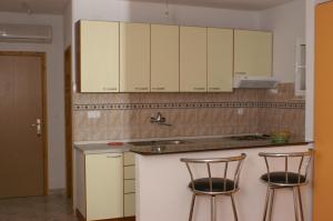 a kitchen with white cabinets and two bar stools at Studio Milna 3074c in Hvar
