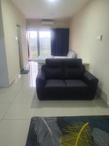 a black couch in a living room with a bed at Lovely studio condo with balcony & pool @ Suria Jelutong in Shah Alam