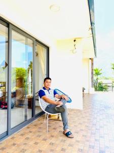 a man sitting in a chair outside of a house at Mai Chau Sunset Boutique Hotel in Mai Chau