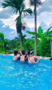 trzy kobiety w wodzie w basenie w obiekcie Mai Chau Sunset Boutique Hotel w mieście Mai Châu