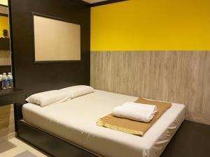 a bedroom with a bed with white sheets and a yellow wall at Best Hotel in Skudai
