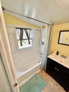 a bathroom with a tub and a sink at Giggling Creek Cottage - BedJet! King Sized! Gazebo, 45 Acres, Arcades, Nintendo, more in Henry