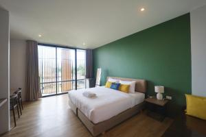 1 dormitorio con 1 cama grande y pared verde en Pugdee Hotel en Lang Suan