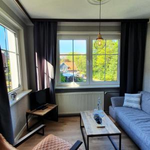 ein Wohnzimmer mit einem blauen Sofa und 2 Fenstern in der Unterkunft Haus Daheim in Braunlage