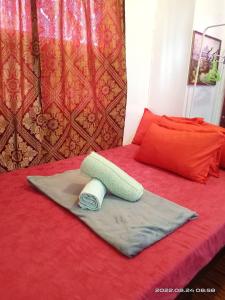 un letto rosso con un asciugamano e un cuscino di Six21 FAMILY UNIT with WIFI FREE! ad Antipolo